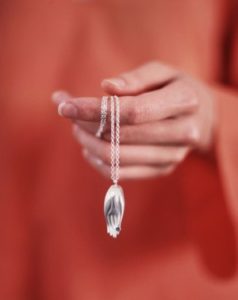 Woman holding necklace with silver hand pendant