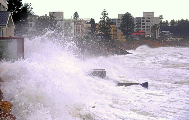 A large wave splashes onto properties located on Collaroy Beach that ...